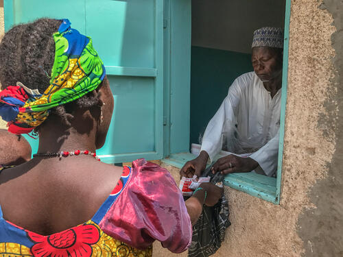 A woman collects ready-to-use therapeutic food for her severely malnourished child at Dan Tchiao health centre in the Zinder region of Niger. May 2019.