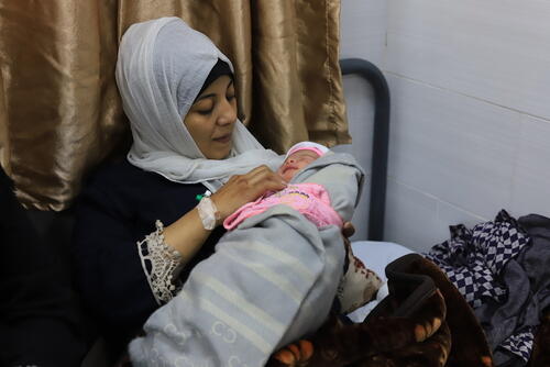 السيدة منى درنة تحمل مولودها الجديد في المستشفى الإماراتي، رفح، غزة.