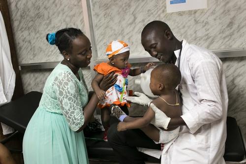 Nine month old Nubia plays with her half brother M'Bemba (14 months) during a medical consultation with Dr. Daouda Berete (r) and Medecins Sans Frontieres (MSF) Health Promoter Camara Djenab (l), herself an Ebola survivor; at the MSF facility in Nongo, Conakry.