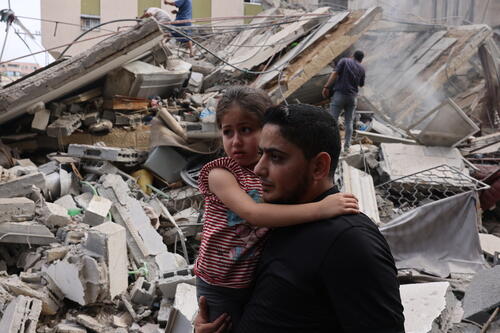 A man carries a child through the devastation in Gaza.