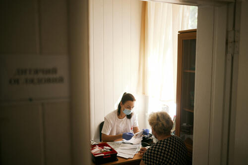 A patient is attending an MSF medical consultation in Chornomorka, Mykolaiv region. 

In a queue of seven people outside the village clinic in Chornomorka,there is a lively discussion. Most of the people are elderly women, and their topic of the day is the diet that many of them have been prescribed by their doctor due to hypertension. 

Here, in the community, 15 km from the frontline, about 2,000 people live. Their family doctors left for safer areas at the beginning of 2022, so now they have to travel to Ochakiv or Mykolaiv to see the nearest doctors. For some residents of this community, it is simply impossible to cover many kilometers on their own bicycles. That is why our medical team supports the residents.   

“I live in Chornomorka with my husband and sister, who has a first-degree disability. It is impossible to take my sister anywhere outside the village, even driving her 5 km to the hospital in Ochakiv is difficult, and recommendations regarding her condition are very necessary, and my husband and I are no longer young,” says Anna Nadobko. The woman is 61 years old, and today her eyes are shining because the doctor said that her blood pressure has finally normalised. 

MSF continues to work in areas close to the frontline, providing free medical care to people in need.