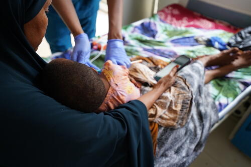 An MSF nurse provides emergency care to a malnourished child at the MSF-supported Bay Regional Hospital in Baidoa as the mother holds her child during treatment.