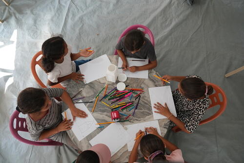 Children draw together around a shared table during a creative activity forming part of MSF's carnival session of games and entertainment for children at the Al Zaytoun Advanced Medical Point in Gaza City.