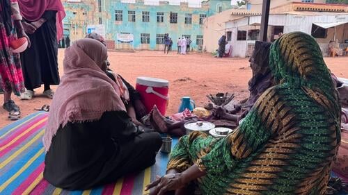 Women sit at around pots of food at one of the largest IDP camps in El Obeid where an MSF emergency team have begun working to expand capacity building, health promotion, and cholera response.