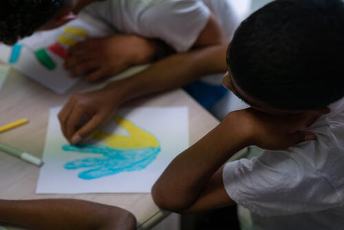 The young migrants are  working at the psycho-educational laboratory: through colours, they talk about the emotions they feel, learning to recognise and represent them. Each colour represents a different emotion, and the kids colour their hands according to what they feel. Many of the young people often express their happiness at having survived the difficult journey, but also their fear of being separated from their travelling companions, or not finding work, and of not being able to support their families.