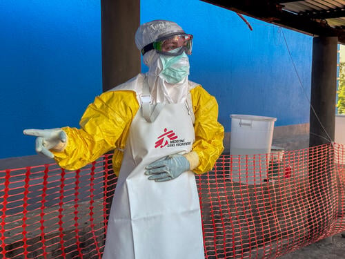 An MSF nurse in full personal protective equipment (PPE) coordinates the arrival of a patient with suspected Ebola disease at the Elikya Ebola Treatment Center (ETC) in Bunia, Ituri province, DR Congo, guiding the patient through the designated circuit for safe admission.