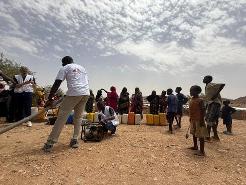 Médecins Sans Frontières (MSF) team members work on water distribution facilities in Metché refugee camp, eastern Chad, while being observed by members of the community. Technical monitoring and maintenance of the infrastructure help ensure the continuity of water services.