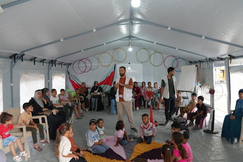 An MSF mental health counsellor, Mahmoud Al-Balbisi, leads a session for children and caregivers inside one of the medical point's tents. Many of them are displaced families from the surrounding area. Gaza City.