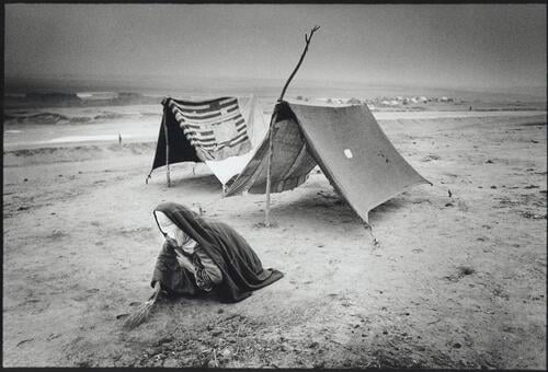 Meymaneh, IDP camp of XSP.A woman is cleaning up the camp.