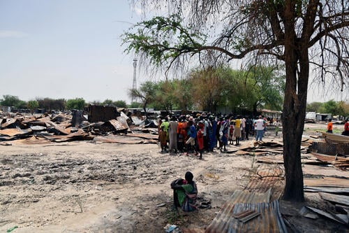 People gather next to what once was a market in Lankien