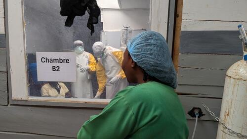 Une membre des équipes MSF regarde ses collègues en consultation avec un patient qui souffre d’Ebola. Centre de traitement Ebola de Kitatumba à Butembo. Septembre 2026.