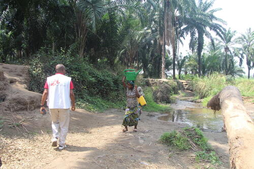 An MSF Water, Sanitation and Hygiene technician on a supervisory visit to water chlorination sites encounters a woman who has just drawn water from the Luke River in the village of Katanga, Fizi territory, South Kivu, Democratic Republic of Congo.