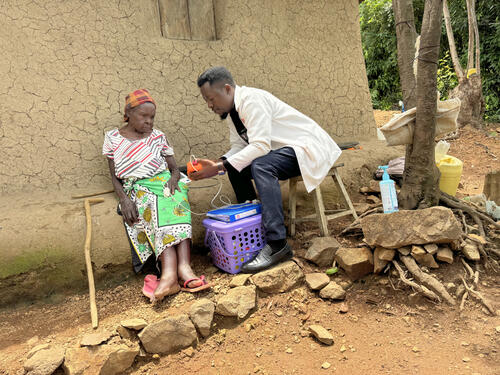 Victor Oriema, a palliative care nurse, checks on Monica during a visit to her home in Homa Bay, Kenya