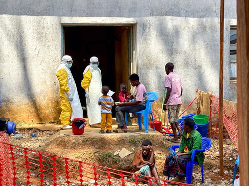 Two healthcare workers speak with patients admitted for confirmed Ebola disease at the MSF ETC in Bambu.