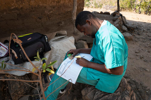 Wilfred Nkhambule, a palliative care nurse with Doctors Without Borders (MSF), fills in Aida Mailosi's consultation booklet during a home visit in Lirangwe, in Blantyre district, on July 21, 2026.