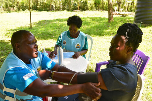 Serfine Gwayo, a community health promoter (left) tests a patient during a DSD group formation session in Nyalkinyi Health Facility