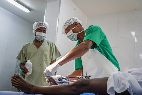 Des médecins pratiquent une intervention chirurgicale sur un jeune homme blessé par une balle. L’'escalade de la violence en Ituri a un impact dévastateur sur la population et crée un besoin urgent de fournir des soins médicaux spécialisés aux personnes blessées à cause du conflit. En réponse, MSF a ouvert, en 2023, un projet de chirurgie traumatologique et propose des soins post opératoires au sein de la clinique Salama. Depuis mi-2023, les équipes médico-chirurgicales du projet ont réalisé plus de 4200 interventions chirurgicales.