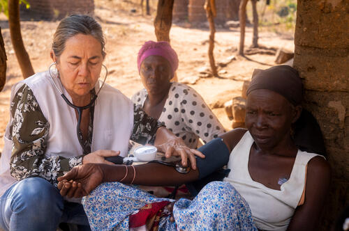 A member of the MSF palliative care team takes the blood pressure of Aida Mailosi, 66, as her daughter and caregiver, Rose Naisoni, looks on, in Lirangwe, in Blantyre district, Malawi, on July 21, 2026. Ill for eight years, Aida could no longer walk because of sores, so the team began coming to her home once a month.