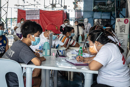 An MSF volunteer interviews a resident of Tondo at the MSF mobile TB screening site in Barangay 133 covered court in Tondo, Manila, the Philippines, March 1, 2023.