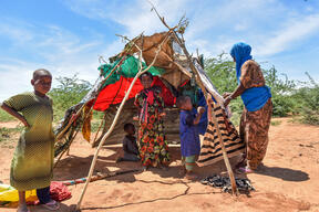 A new arrival in Dagahaley sets up a makeshift tent that will be her new shelter in Dagahaley; her children lay in wait for their new shelter