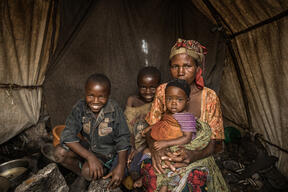 Foibe Bonane with her three children inside their tent in Rusayo camp