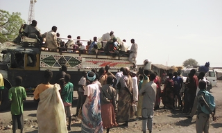 People  load into trucks to go to Sudan