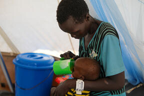 A mother feeds her child at the inpatient therapeutic feeding centre