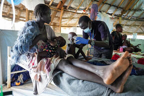An MSF nurse helps a 2-year-old take liquid milk