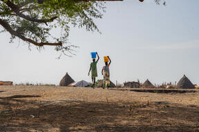 Two women carrying water on their heads from the river