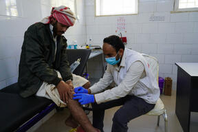 MSF nurse Amer checks the injury of Abdullah