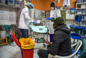 A patient, waits as MSF clinicians prepare to tend to his injuries.