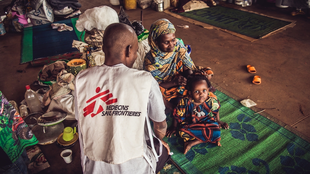 An MSF member talks to  displaced mom with her kid