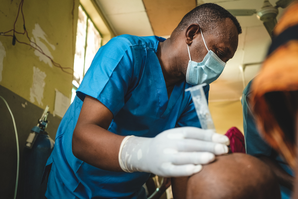 An MSF doctor attends to a child’s [being held by their guardian] feeding at the inpatient therapeutic feeding centre.