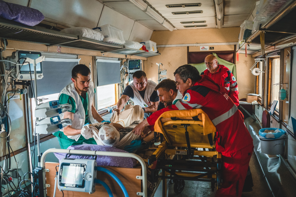 A severely war-wounded patient is transferred by a Ukrainian ambulance crew into an intensive care bed on board the train