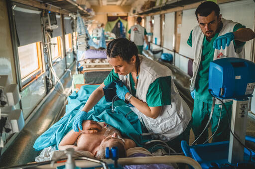 On board MSF's evacuation train, medics check an intensive care patient during a journey to Lviv